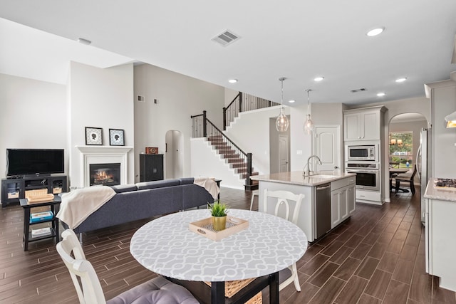 6303 Grand Drift Ct, Katy, TX 77494 - dining area with arched walkways, stairway, dark wood finished floors, recessed lighting, and a glass covered fireplace