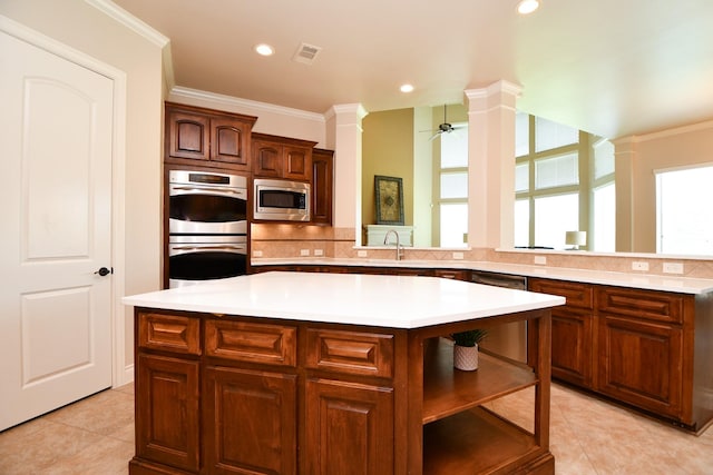 8706 Stowe Creek Ln, Missouri City, TX 77459 - kitchen featuring appliances with stainless steel finishes, a center island, light tile patterned floors, light countertops, and ornamental molding