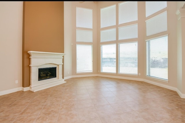 8706 Stowe Creek Ln, Missouri City, TX 77459 - unfurnished living room with light tile patterned floors, healthy amount of natural light, a premium fireplace, and a towering ceiling