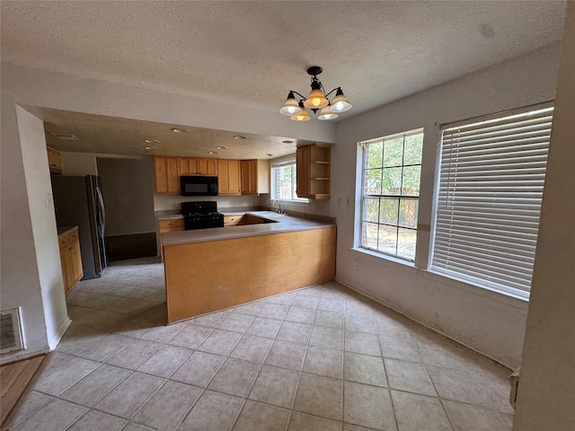 3 Ridgeline Ct, The Woodlands, TX 77381 - kitchen featuring black appliances, light tile patterned floors, a peninsula, a textured ceiling, and a chandelier