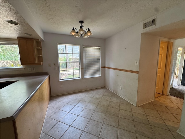 3 Ridgeline Ct, The Woodlands, TX 77381 - unfurnished dining area featuring a textured ceiling, a chandelier, healthy amount of natural light, and light tile patterned flooring