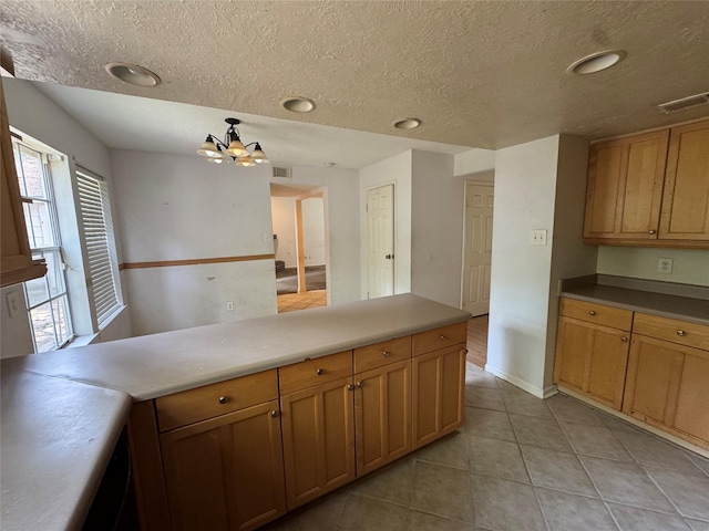 3 Ridgeline Ct, The Woodlands, TX 77381 - kitchen with light tile patterned floors, a chandelier, a textured ceiling, recessed lighting, and brown cabinetry