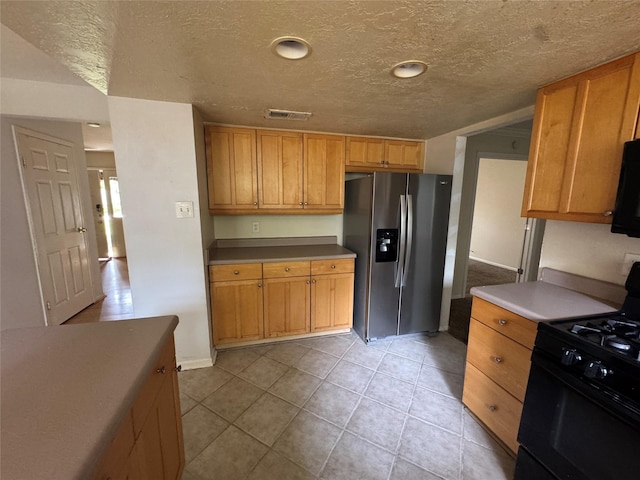 3 Ridgeline Ct, The Woodlands, TX 77381 - kitchen featuring stainless steel fridge, black range with gas cooktop, a textured ceiling, and light tile patterned floors