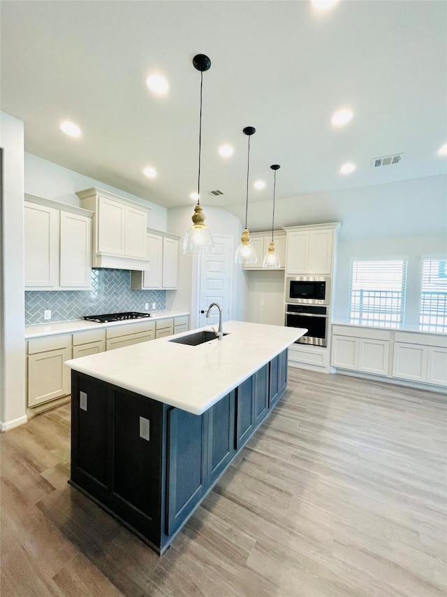 669 Cape Capri Dr, Katy, TX 77493 - kitchen featuring stainless steel oven, black microwave, white cabinetry, light wood finished floors, and tasteful backsplash