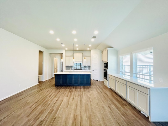 669 Cape Capri Dr, Katy, TX 77493 - kitchen with stainless steel appliances, backsplash, light countertops, white cabinetry, and light wood-style flooring