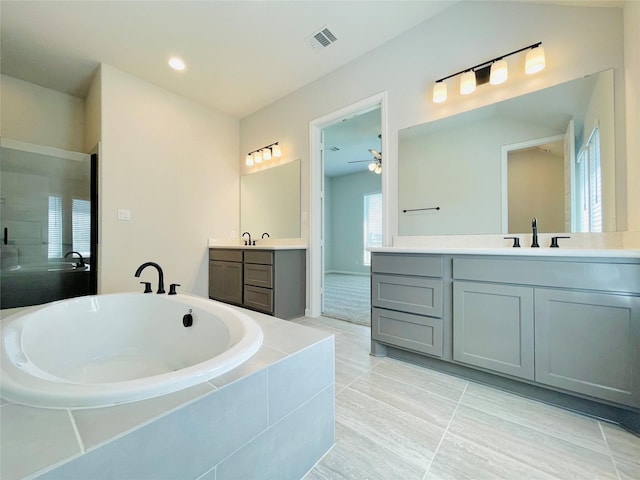 669 Cape Capri Dr, Katy, TX 77493 - bathroom featuring tiled bath, two vanities, a ceiling fan, tile patterned flooring, and tiled shower
