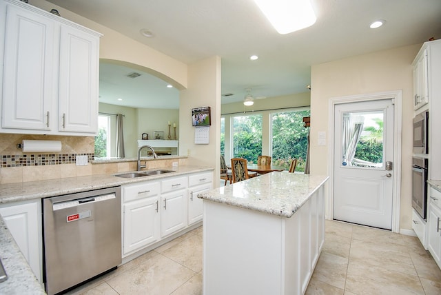 1006 Pointe Loma Dr, Sugar Land, TX 77479 - kitchen featuring appliances with stainless steel finishes, a kitchen island, white cabinets, tasteful backsplash, and recessed lighting