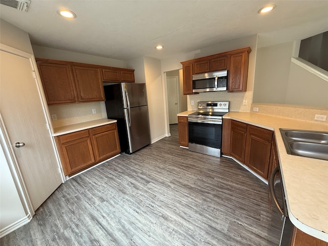 2325 Shady Tree Ln, Conroe, TX 77301 - kitchen with stainless steel appliances, wood finished floors, light countertops, recessed lighting, and brown cabinetry