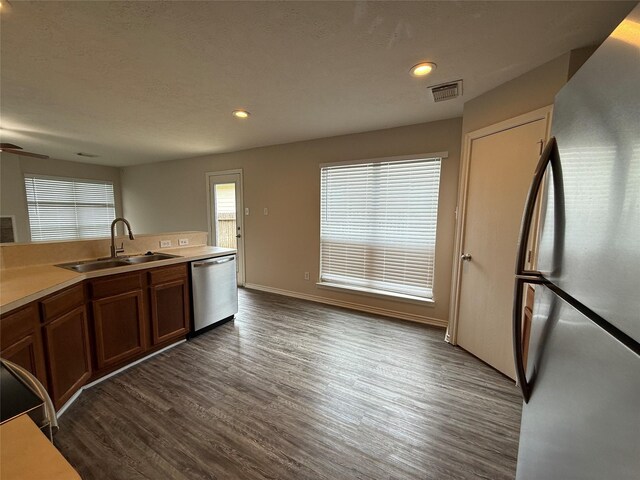 2325 Shady Tree Ln, Conroe, TX 77301 - kitchen with appliances with stainless steel finishes, dark wood finished floors, brown cabinetry, light countertops, and recessed lighting