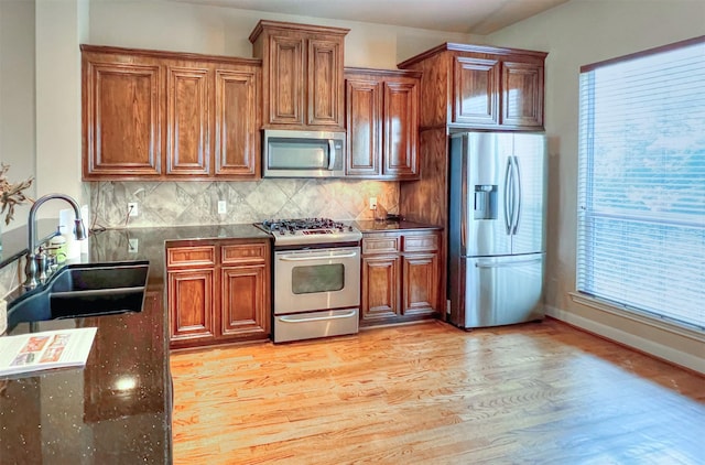 2325 Hutchins St, Houston, TX 77004 - kitchen featuring stainless steel appliances, light wood-style floors, backsplash, brown cabinets, and plenty of natural light