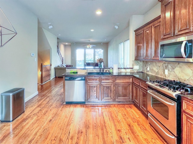 2325 Hutchins St, Houston, TX 77004 - kitchen featuring appliances with stainless steel finishes, a peninsula, a ceiling fan, open floor plan, and light wood-style floors