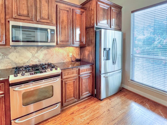 2325 Hutchins St, Houston, TX 77004 - kitchen featuring stainless steel appliances, tasteful backsplash, dark countertops, light wood-type flooring, and brown cabinets