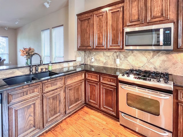 2325 Hutchins St, Houston, TX 77004 - kitchen featuring stainless steel appliances, backsplash, brown cabinetry, and light wood-style floors