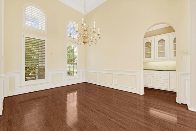 16506 Emilia Ct, Spring, TX 77379 - unfurnished dining area featuring a chandelier, dark wood finished floors, wainscoting, a decorative wall, and a towering ceiling
