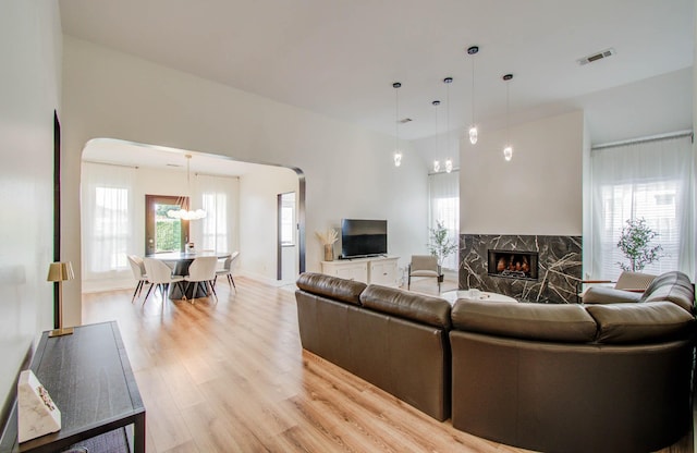 4426 Innsbrook Pl, Sugar Land, TX 77479 - living room with arched walkways, a chandelier, a fireplace, and light wood-style flooring