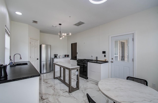 4426 Innsbrook Pl, Sugar Land, TX 77479 - kitchen with black gas range, light marble finish flooring, white cabinetry, dark countertops, and hanging light fixtures