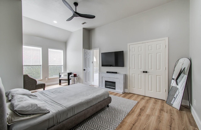 4426 Innsbrook Pl, Sugar Land, TX 77479 - bedroom with light wood-style floors, a closet, high vaulted ceiling, a glass covered fireplace, and ceiling fan