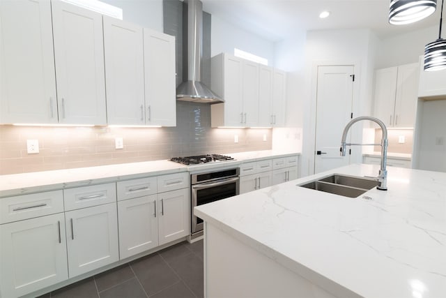 1202 Hamblen St, Houston, TX 77009 - kitchen featuring wall chimney range hood, appliances with stainless steel finishes, decorative backsplash, white cabinetry, and recessed lighting
