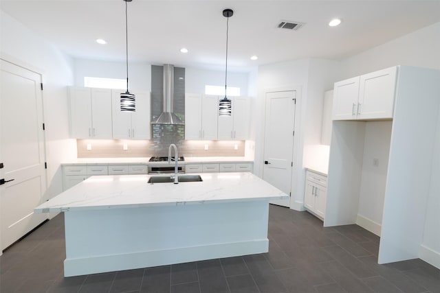 1202 Hamblen St, Houston, TX 77009 - kitchen with wall chimney exhaust hood, backsplash, light stone counters, a center island with sink, and white cabinetry