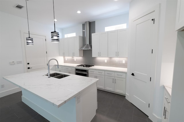 1202 Hamblen St, Houston, TX 77009 - kitchen featuring wall chimney range hood, stainless steel appliances, decorative backsplash, white cabinets, and a center island with sink