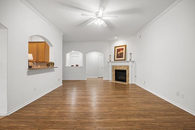 2206 Hollow Bloom Ln, Katy, TX 77494 - unfurnished living room with ceiling fan, ornamental molding, dark wood-style flooring, a tile fireplace, and arched walkways