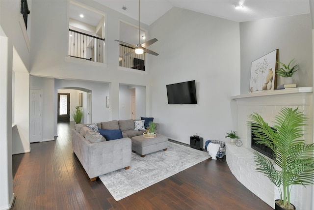 8106 Yarrow Dr, Cypress, TX 77433 - living room with arched walkways, dark wood finished floors, ceiling fan, a towering ceiling, and a brick fireplace