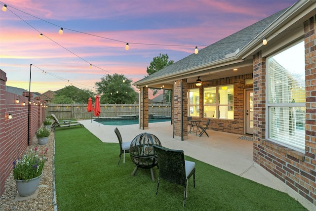 8106 Yarrow Dr, Cypress, TX 77433 - yard at dusk with a fenced backyard, a ceiling fan, an outdoor fire pit, and a patio