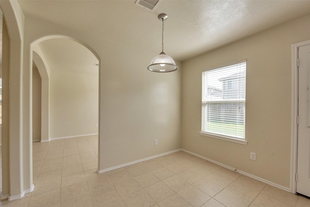 12807 Maybank Shores Ct, Houston, TX 77045 - unfurnished room featuring light tile patterned floors, arched walkways, and a textured ceiling