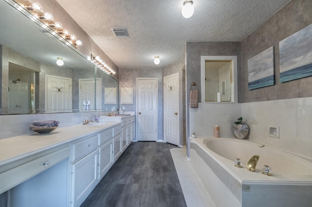 2601 Sailboat Dr, Houston, TX 77058 - bathroom with a bath, double vanity, wood finished floors, a shower with shower door, and a textured ceiling