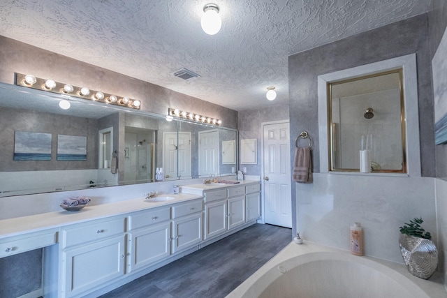 2601 Sailboat Dr, Houston, TX 77058 - full bathroom with a bath, double vanity, a stall shower, wood finished floors, and a textured ceiling