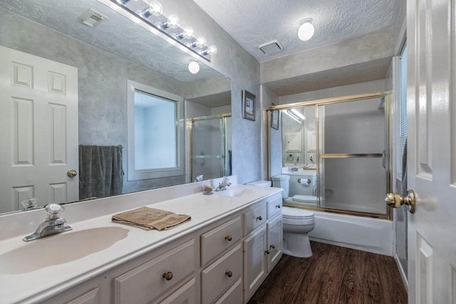 2601 Sailboat Dr, Houston, TX 77058 - full bath with wood finished floors, double vanity, combined bath / shower with glass door, and a textured ceiling