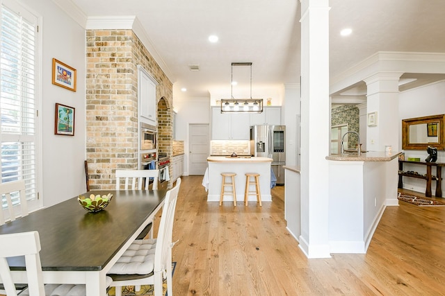 2442 Chimney Rock Rd, Houston, TX 77056 - dining space featuring ornate columns, light wood-type flooring, ornamental molding, and recessed lighting