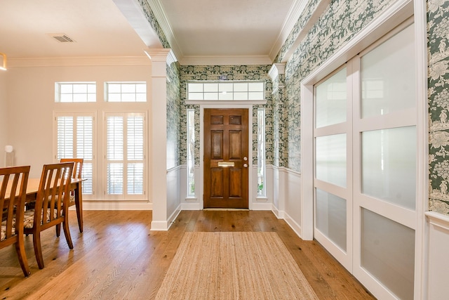 2442 Chimney Rock Rd, Houston, TX 77056 - entryway featuring wallpapered walls, wood finished floors, ornamental molding, plenty of natural light, and a wainscoted wall