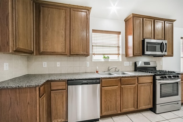 5919 Glenneyre Ln, Houston, TX 77084 - kitchen with appliances with stainless steel finishes, brown cabinets, backsplash, and light tile patterned floors