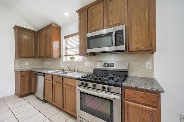 5919 Glenneyre Ln, Houston, TX 77084 - kitchen featuring stainless steel appliances, backsplash, lofted ceiling, brown cabinetry, and light tile patterned floors