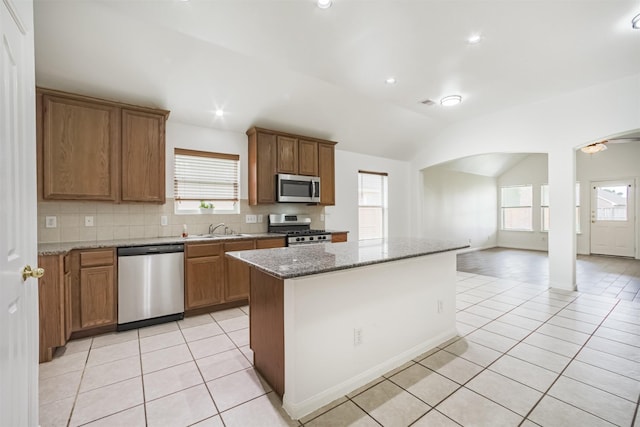 5919 Glenneyre Ln, Houston, TX 77084 - kitchen with appliances with stainless steel finishes, light tile patterned floors, vaulted ceiling, brown cabinets, and recessed lighting