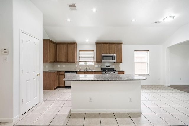 5919 Glenneyre Ln, Houston, TX 77084 - kitchen with appliances with stainless steel finishes, vaulted ceiling, light tile patterned floors, and brown cabinetry