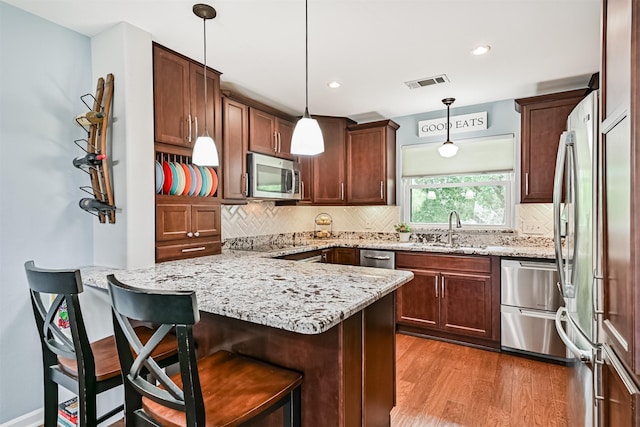 2114 Crows Nest Dr, League City, TX 77573 - kitchen with appliances with stainless steel finishes, a peninsula, light wood-style flooring, backsplash, and light stone countertops