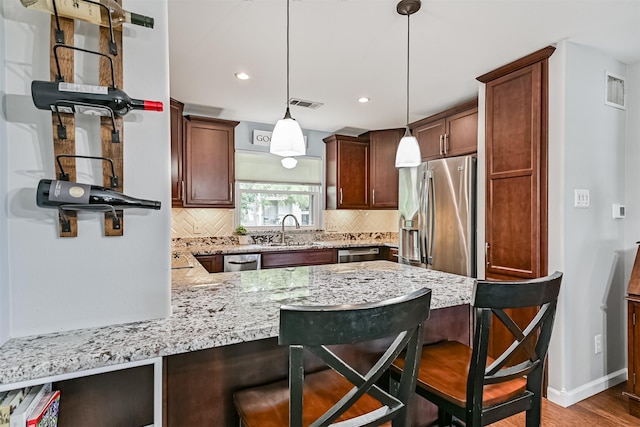 2114 Crows Nest Dr, League City, TX 77573 - kitchen with appliances with stainless steel finishes, backsplash, a kitchen bar, light stone countertops, and a peninsula