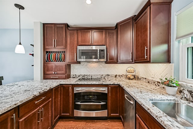 2114 Crows Nest Dr, League City, TX 77573 - kitchen featuring appliances with stainless steel finishes, backsplash, light stone counters, decorative light fixtures, and wood finished floors