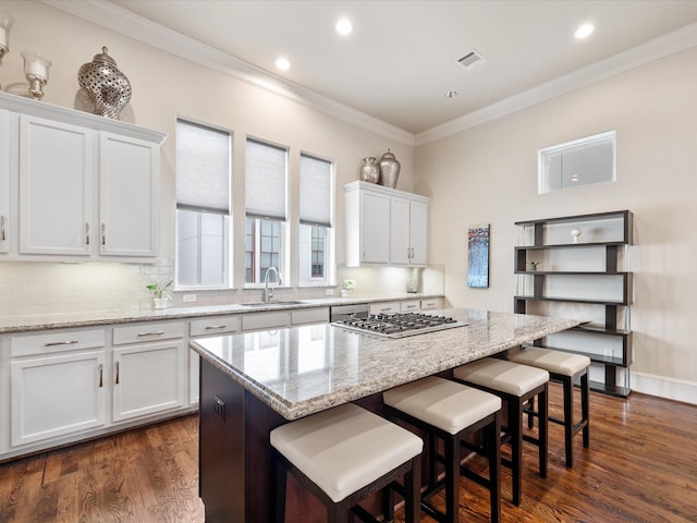 249 E 27th St, Houston, TX 77008 - kitchen featuring a kitchen island, white cabinets, ornamental molding, dark wood-style floors, and a breakfast bar area