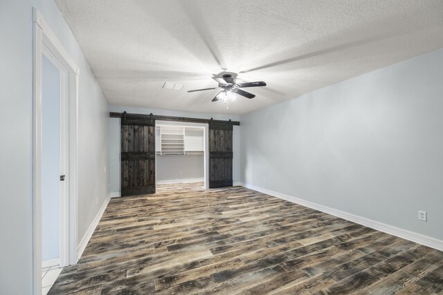 2919 Lake View Dr, Missouri City, TX 77459 - unfurnished bedroom featuring a barn door, dark wood-type flooring, a textured ceiling, and ceiling fan