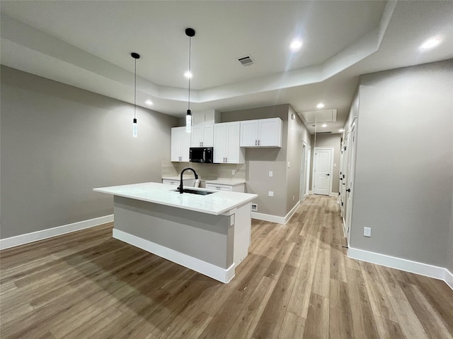 7921 Virgil St, Houston, TX 77088 - kitchen featuring black microwave, a raised ceiling, light wood finished floors, white cabinets, and recessed lighting