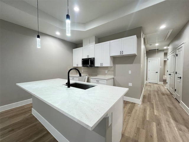 7921 Virgil St, Houston, TX 77088 - kitchen with black microwave, light wood-type flooring, white cabinets, recessed lighting, and hanging light fixtures