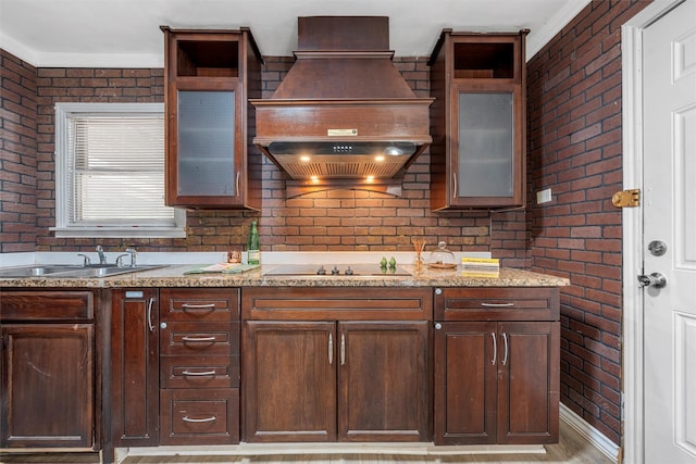 4505 Memorial Dr, Waco, TX 76711 - kitchen featuring brick wall, premium range hood, light stone countertops, dark brown cabinetry, and open shelves