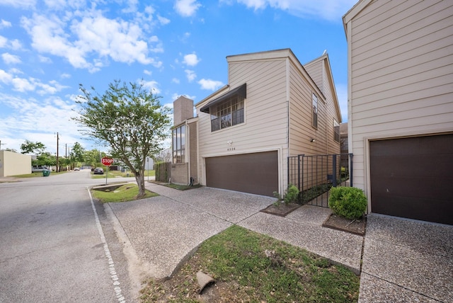 4904 Feagan St Unit 1, Houston, TX 77007 - view of property exterior featuring an attached garage, concrete driveway, and a chimney