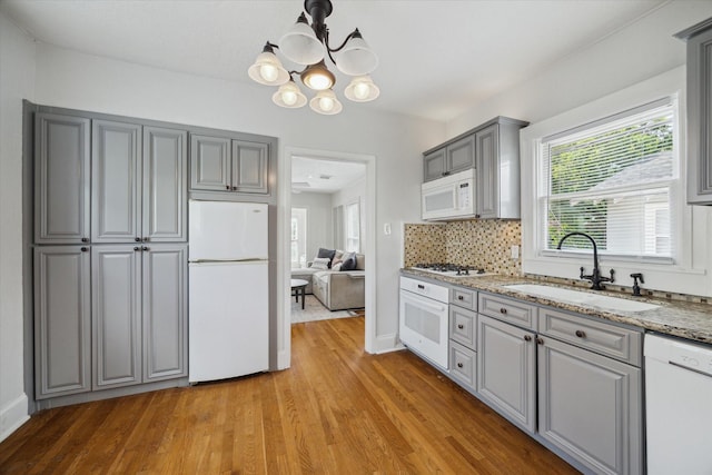 2317 Ashland St, Houston, TX 77008 - kitchen featuring white appliances, gray cabinetry, light wood-type flooring, and a chandelier