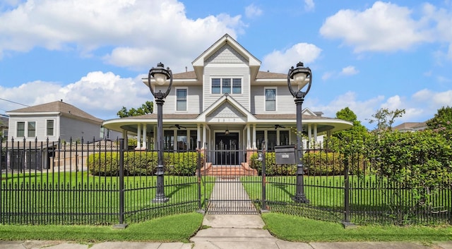 2317 Ashland St, Houston, TX 77008 - victorian-style house featuring a porch, ceiling fan, a fenced front yard, a gate, and a shingled roof