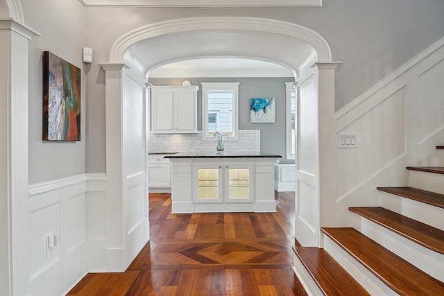 2317 Ashland St, Houston, TX 77008 - hallway with decorative columns, arched walkways, a decorative wall, stairway, and a wainscoted wall