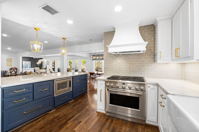 12215 Cobblestone Dr, Houston, TX 77024 - kitchen with stainless steel appliances, premium range hood, white cabinets, blue cabinets, and tasteful backsplash